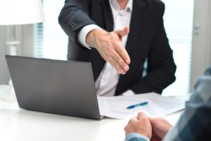 Licensed moneylender in black suit and white shirt extends hand to loan applicant in Singapore
