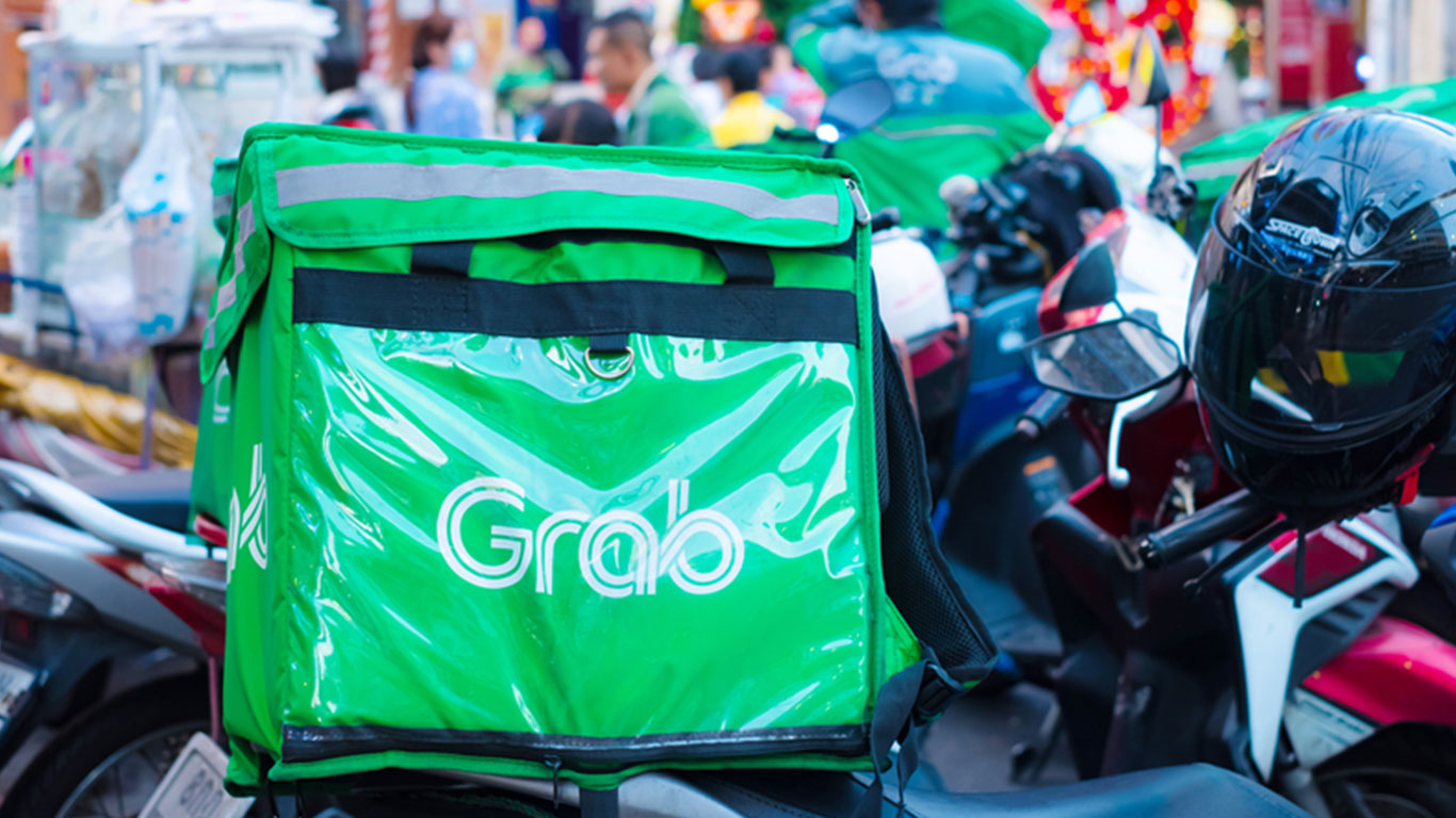 Green Grab delivery bag and black helmet on a parked motorcycle in Singapore