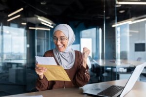 Happy Muslim woman in an office receiving a money loan in Singapore