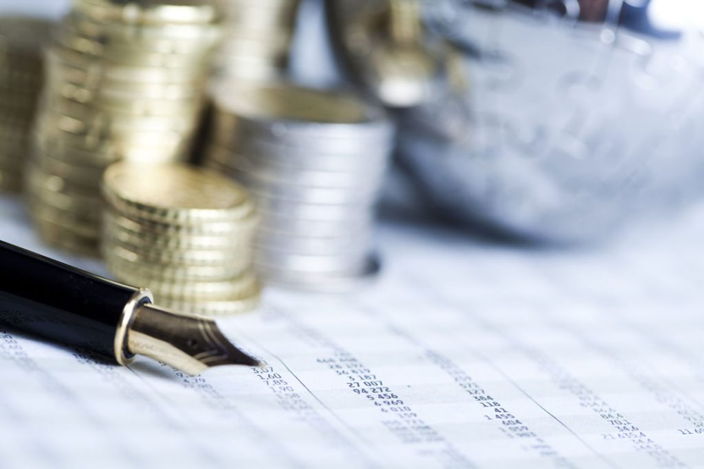 Coins stacked up on calculations report and fountain pen showing the search for the cheapest loan in Singapore