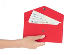 Hand holding red envelope filled with fifty-dollar notes after a successful application for a cash loan in Singapore